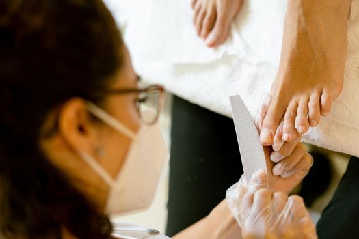 Beautician giving a pedicure painting her client's nails in a beauty centre. Business and beauty concepts