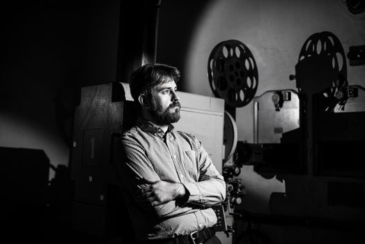 beautiful hipster man standing near a film projector in the room projectionist