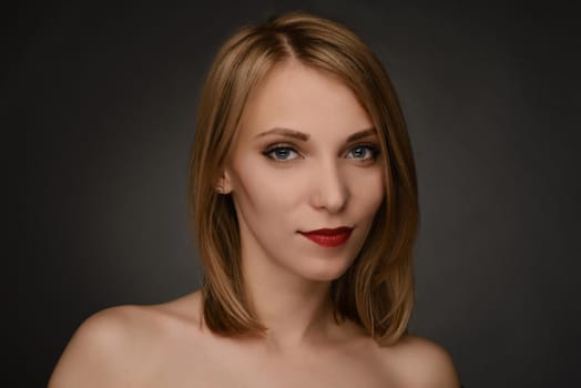 young blonde smiling blonde woman portrait isolated on gray background