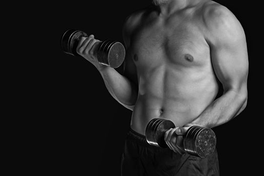 Unrecognizable muscular man exercises with metal dumbbells, monochrome image