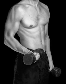 Muscular man makes exercises with dumbbells, monochrome image