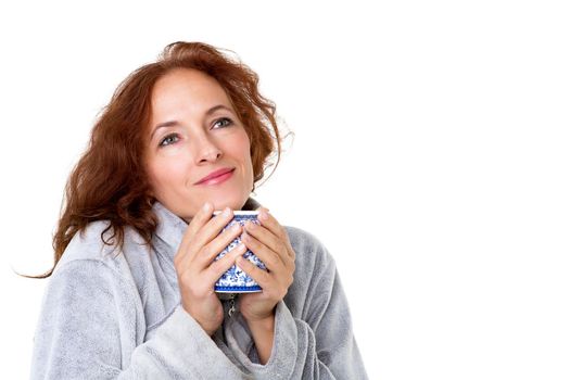 Smiling woman holding porcelain mug. Cheerful brown haired woman posing with cup of coffee or tea in her hands against white background. Female person enjoying of hot drink in the morning