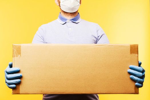 Man holding cardboard boxes in medical rubber gloves and mask. Coronavirus pandemic quarantine delivery concept