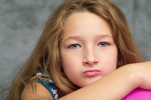 Close up portrait of cute preteen girl. Pretty girl with blonde long hair looking at camera. Preteen child posing in studio