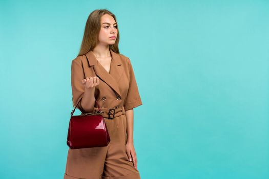 Young fashion woman hold handbag clutch isolated on blue background - image