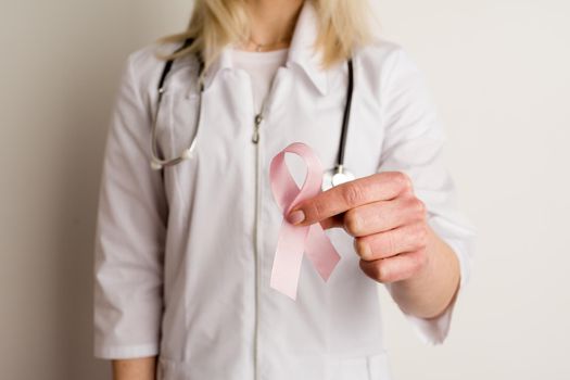 Woman doctor holding a pink ribbon in her hands - image