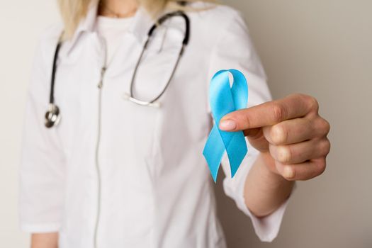 Female doctor holding a blue ribbon in her hands - image
