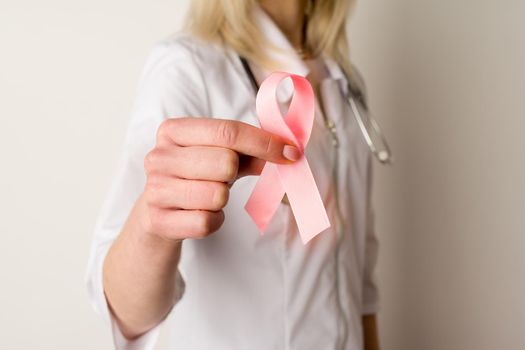 Woman doctor holding a pink ribbon in her hands - image