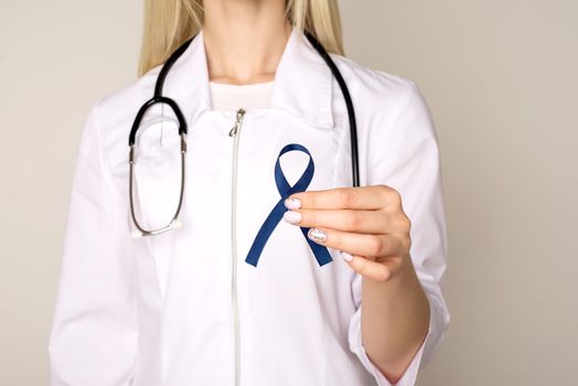Doctor hands holding blue ribbon, diabetes and Colorectal Cancer Awareness - Image