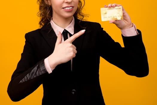 Portrait of a beautiful young business woman standing isolated over yellow background, holding credit card - image