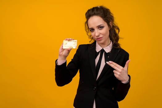 Portrait of a beautiful young business woman standing isolated over yellow background, holding credit card - image