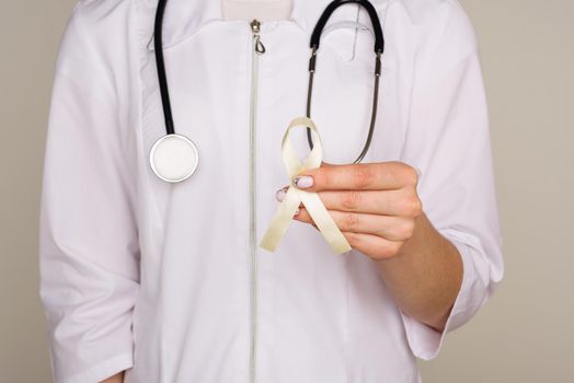 Yellow ribbon symbolic color for Sarcoma Bone cancer, Bladder health, Liver disease, Spina Bifida Awareness Month and suicide prevention in doctor's hand - Image