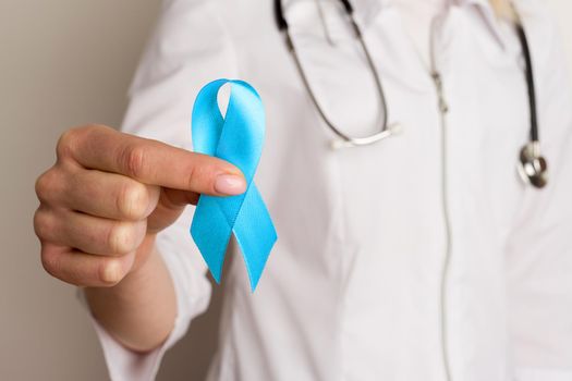 Female doctor holding a blue ribbon in her hands - image