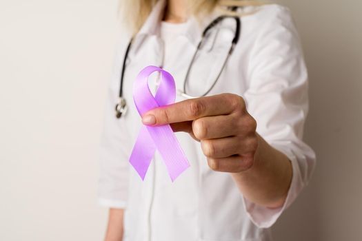 Woman doctor holding a purple ribbon in her hands - image