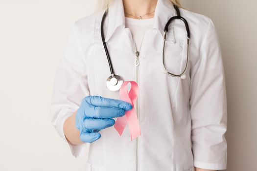 Woman doctor holding a pink ribbon in her hands - image