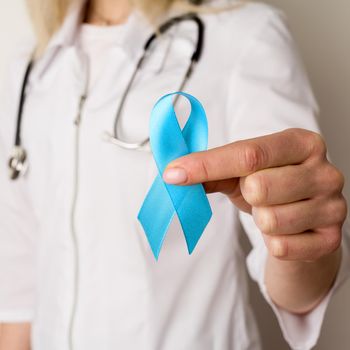 Female doctor holding a blue ribbon in her hands - image