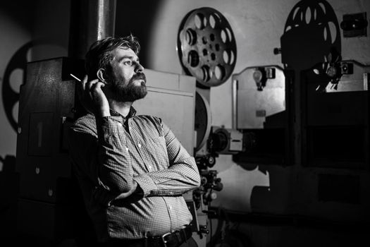 beautiful hipster man standing near a film projector in the room projectionist