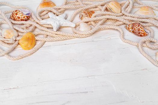Sea shells with rope on white wooden background, copy space. Summer vacation concept