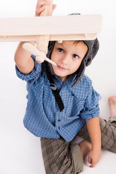 little boy with pilot hat and toy airplane sitting isolated on white background