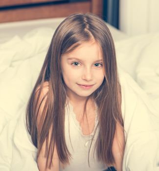 cute little girl lying in a bad under a blanket