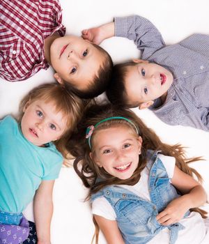 children lying head to head on the floor isolated on white background