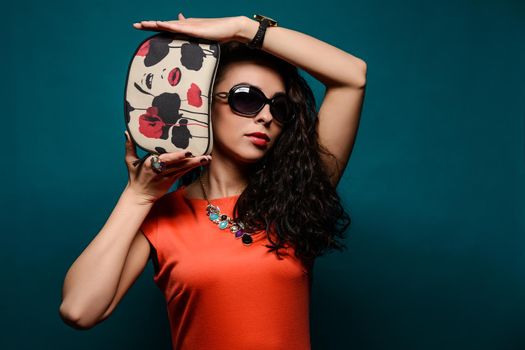 Beautiful girl with a sunglasses and clutch bag in her hands.