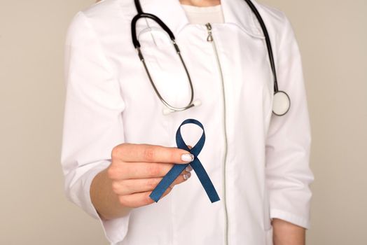 Doctor hands holding blue ribbon, diabetes and Colorectal Cancer Awareness - Image
