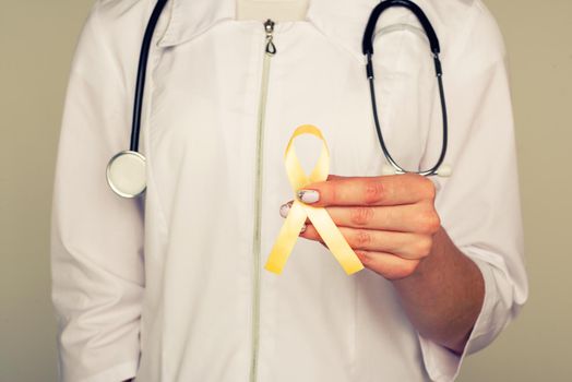 Yellow ribbon symbolic color for Sarcoma Bone cancer, Bladder health, Liver disease, Spina Bifida Awareness Month and suicide prevention in doctor's hand - Image