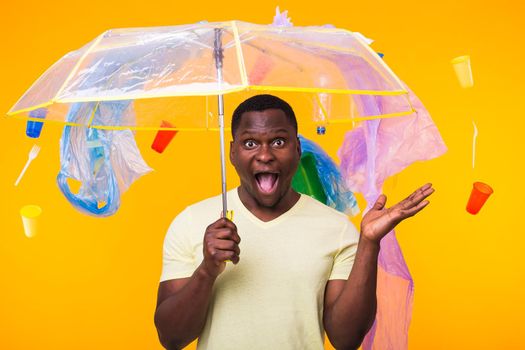 Plastic recycling problem, ecology and environmental disaster concept - Scared man screaming on yellow background with trash. He is worried about ecology disaster.