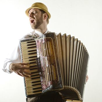 Portrait of professional musician with accordion at white wall