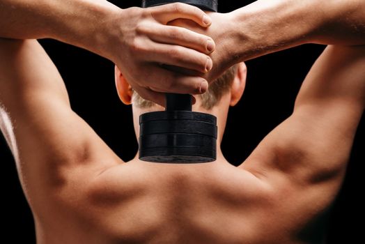 Unrecognizable man holds dumbbell, rear view