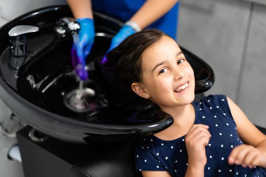 little girl dyes her hair purple in a hairdressing salon