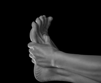Woman holds her foot, pain in the foot, monochrome image