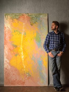 Portrait Of Male Artist standing next to his abstract painting in the Studio.