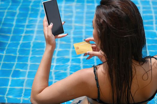 online payment, A teenage girl who swims is using her credit card with her phone to make purchases. online via internet