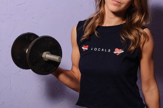 sports girl in a black shirt holding a dumbbell in her hand bent at the elbow