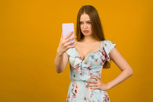 Young woman wears in sunner dress with flowers surprised by the news on a smartphone - image