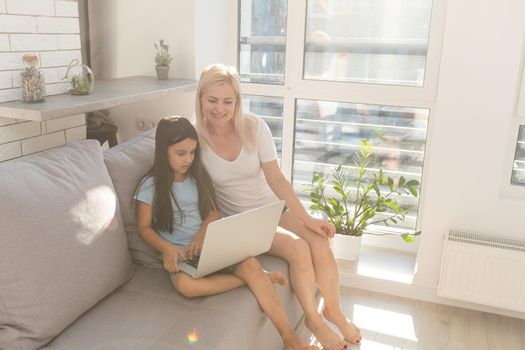 Little girl studying online using her laptop at home