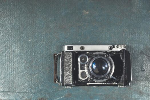 Old vintage camera on a blue scratched background. Focus on the lens.