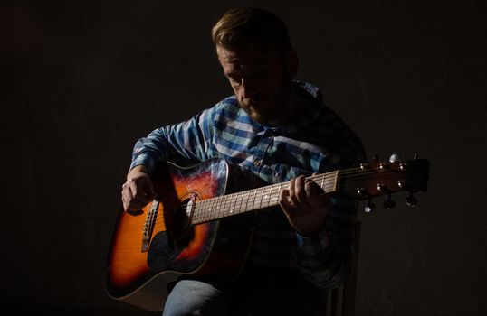 caucasian male jazz musician playing guitar on stage, focus on hand.