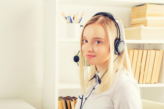 Portrait of happy smiling female customer support phone operator at workplace. - Image toned