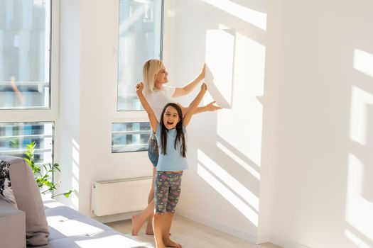 mother and daughter hangs a large photo canvas at home