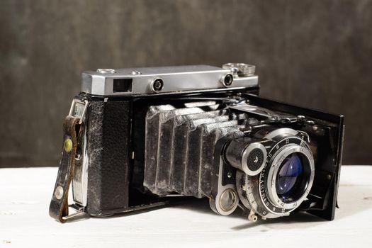Old vintage camera on white wooden table black background.