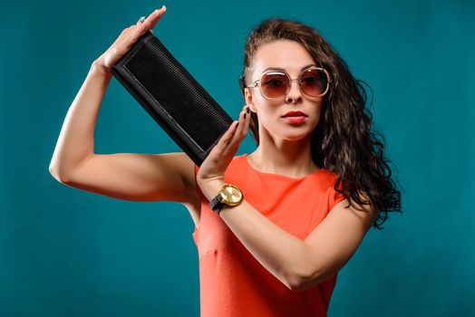 Beautiful girl with a sunglasses and clutch bag in her hands