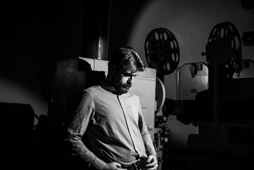 beautiful hipster man standing near a film projector in the room projectionist