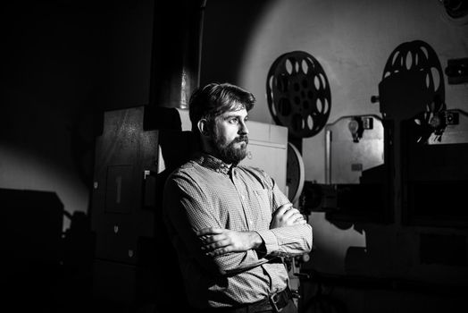 beautiful hipster man standing near a film projector in the room projectionist