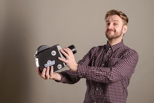 Young attractive cameraman in a plaid shirt takes himself off to an old movie camera.