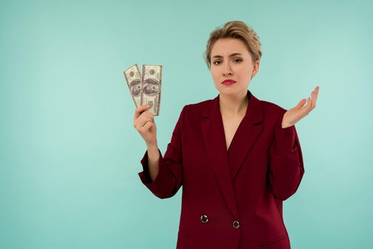 A young businesswoman bankrupt holds in her hands the remaining money. Depressed state on the day of loan payment. On blue background with copyspase