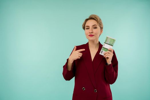 Portrait of beautiful young businesswoman pointing finger at money , on blue background - Image