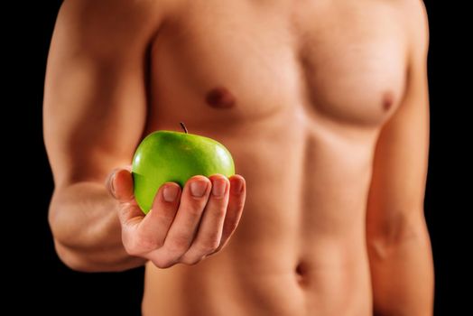 Unrecognizable strong man holds green apple, concept of healthy food